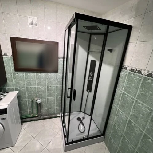Łazienka z czarną kabiną prysznicową i pralką — DobryHydraulik Poznań