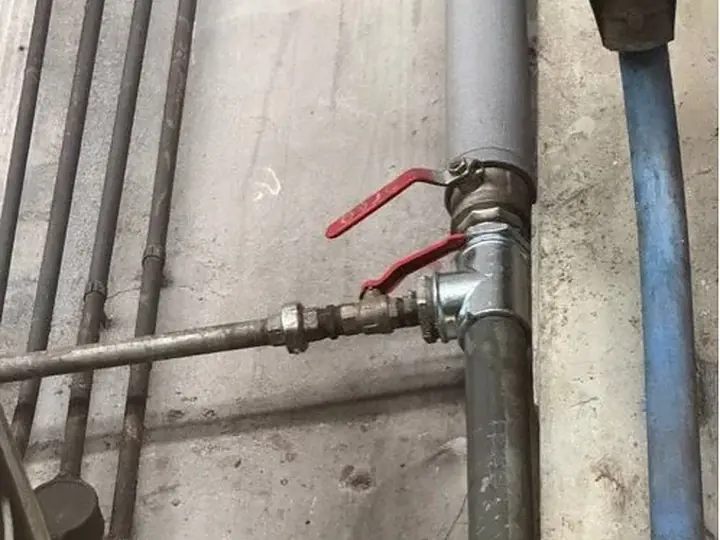 Główny zawór z czerwoną rączką na rurach — DobryHydraulik Poznań